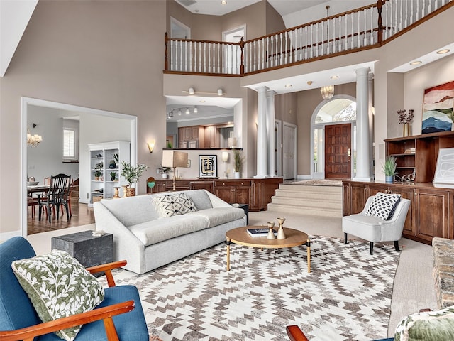 living area with a chandelier, a towering ceiling, and decorative columns