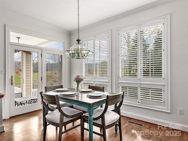 dining area featuring a chandelier, visible vents, crown molding, and wood finished floors