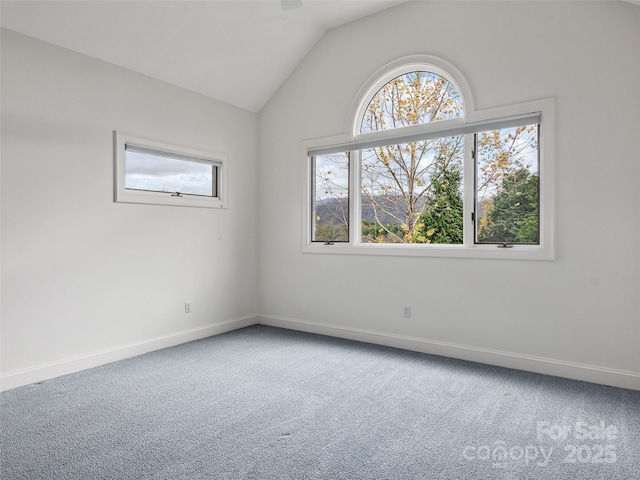 carpeted spare room with vaulted ceiling and baseboards