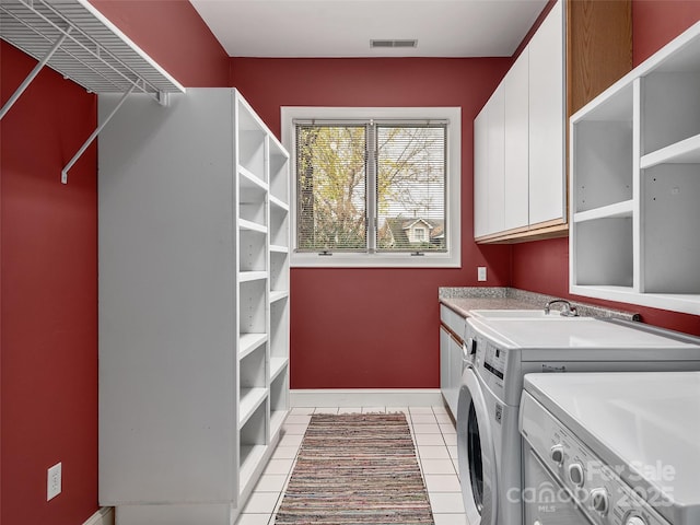 laundry area featuring light tile patterned floors, cabinet space, visible vents, washing machine and dryer, and baseboards