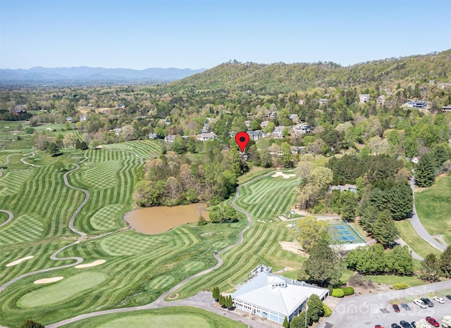 drone / aerial view with view of golf course, a forest view, and a mountain view