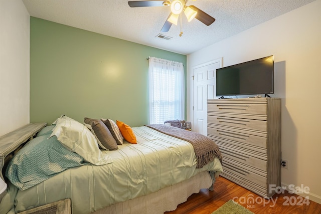 bedroom with ceiling fan, dark hardwood / wood-style flooring, and a textured ceiling