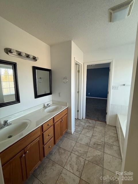 bathroom with a washtub, vanity, tile patterned floors, and a textured ceiling