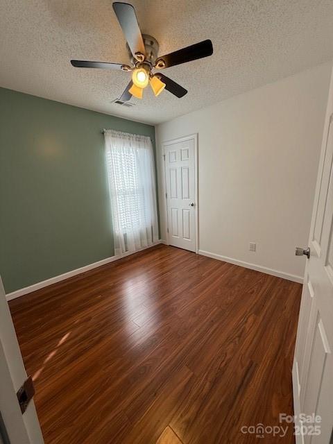 unfurnished bedroom featuring ceiling fan, dark hardwood / wood-style floors, and a textured ceiling