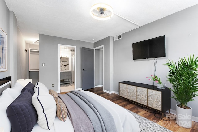 bedroom with connected bathroom, dark wood-type flooring, and a textured ceiling