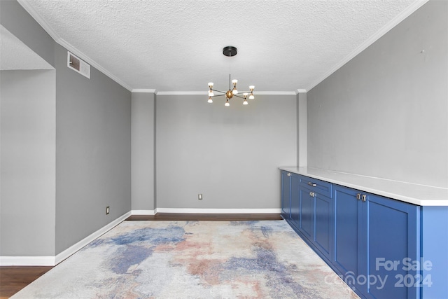 empty room with hardwood / wood-style floors, a notable chandelier, a textured ceiling, and crown molding