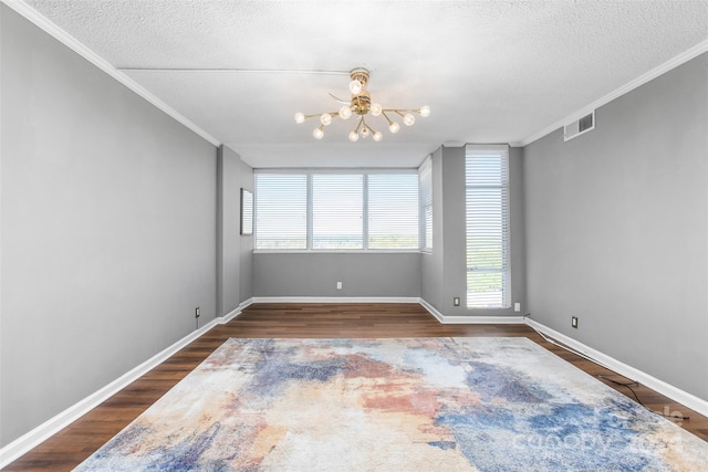 spare room featuring a textured ceiling, plenty of natural light, dark wood-type flooring, and a chandelier