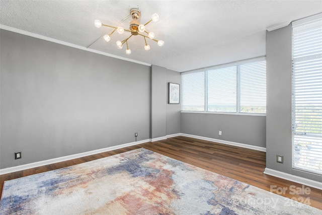 unfurnished room with a textured ceiling, ornamental molding, dark hardwood / wood-style floors, and an inviting chandelier