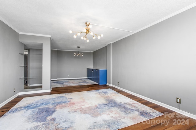 spare room with ornamental molding, a textured ceiling, a notable chandelier, and dark hardwood / wood-style floors