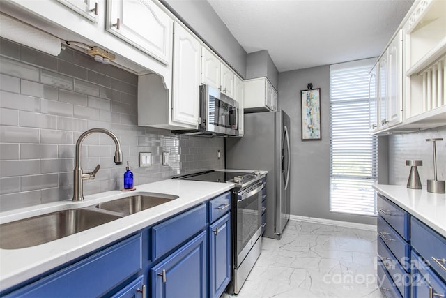 kitchen featuring white cabinets, decorative backsplash, sink, blue cabinetry, and appliances with stainless steel finishes