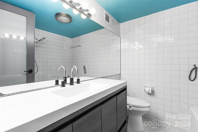 bathroom with tile walls, tile patterned flooring, vanity, and toilet