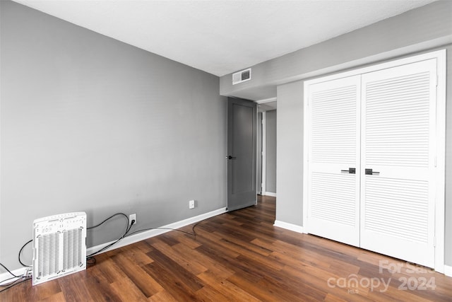 unfurnished bedroom with dark wood-type flooring and a closet