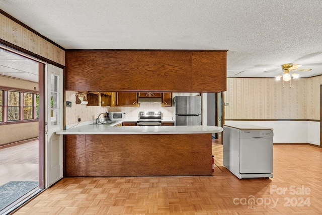 kitchen with kitchen peninsula, ceiling fan, light parquet flooring, and appliances with stainless steel finishes