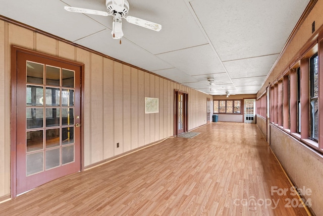 exterior space with ceiling fan, wood walls, and light wood-type flooring