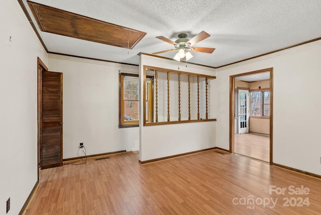 empty room with a textured ceiling, light hardwood / wood-style floors, ceiling fan, and crown molding