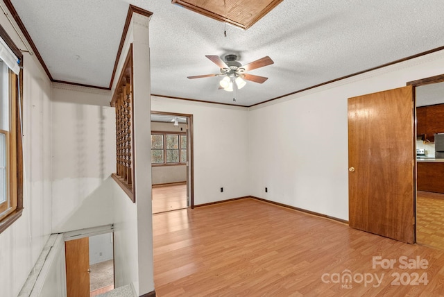 unfurnished room featuring a textured ceiling, light hardwood / wood-style floors, ceiling fan, and ornamental molding