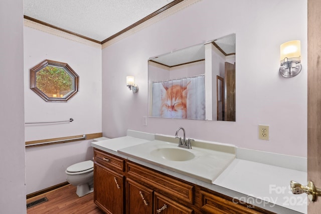 bathroom featuring vanity, a textured ceiling, crown molding, hardwood / wood-style flooring, and toilet