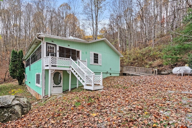 rear view of property featuring a sunroom and a deck