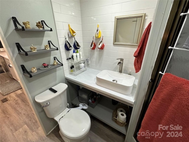 bathroom with tasteful backsplash, toilet, sink, and hardwood / wood-style flooring