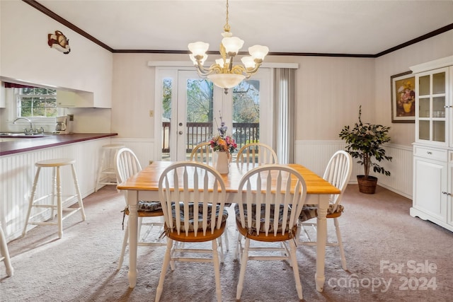 carpeted dining room with a chandelier, a wealth of natural light, and crown molding