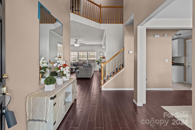 entryway with ceiling fan, a high ceiling, dark wood-type flooring, and a textured ceiling