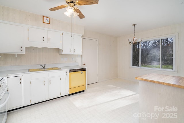 kitchen with dishwashing machine, ceiling fan with notable chandelier, sink, pendant lighting, and white cabinetry