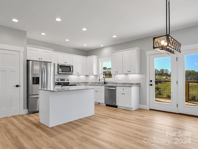 kitchen with stainless steel appliances, a wealth of natural light, white cabinets, and decorative light fixtures