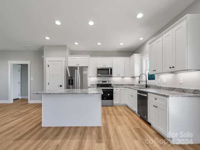 kitchen featuring white cabinetry, sink, appliances with stainless steel finishes, light hardwood / wood-style flooring, and a kitchen island