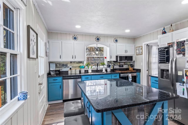 kitchen featuring a wealth of natural light, white cabinetry, a kitchen island, and appliances with stainless steel finishes