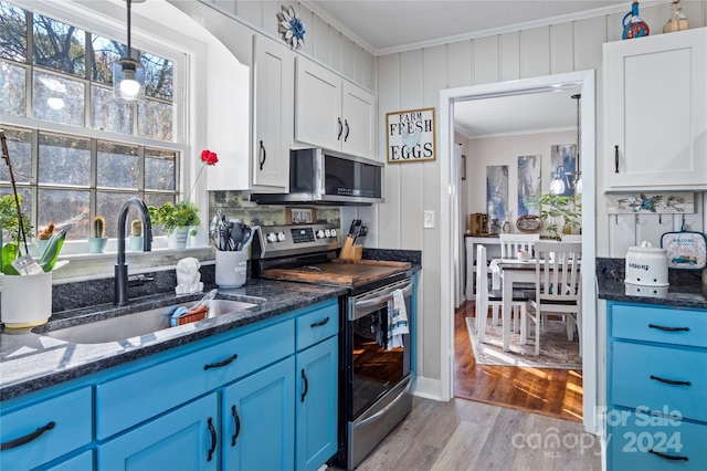 kitchen featuring blue cabinetry, appliances with stainless steel finishes, crown molding, and light wood-type flooring