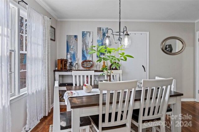 dining area featuring crown molding, dark hardwood / wood-style flooring, and an inviting chandelier