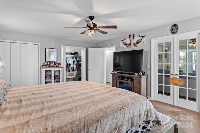 bedroom featuring multiple closets, ceiling fan, hardwood / wood-style floors, and a textured ceiling