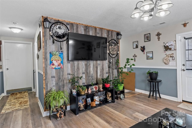 living room with hardwood / wood-style floors, an inviting chandelier, and a textured ceiling