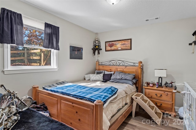 bedroom with light wood-type flooring and a textured ceiling