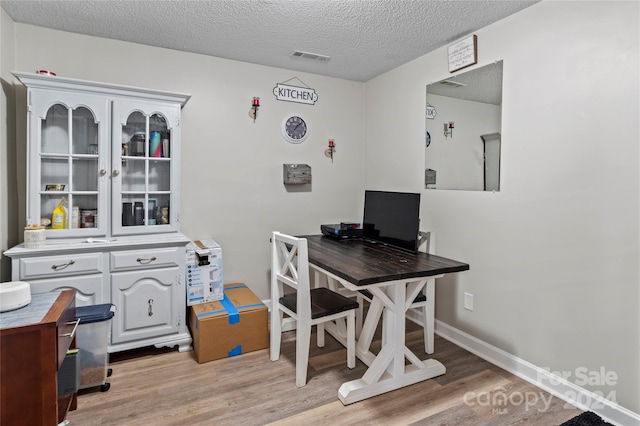 office area with a textured ceiling and light wood-type flooring