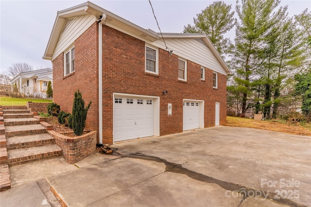 view of side of home featuring a garage, brick siding, and concrete driveway