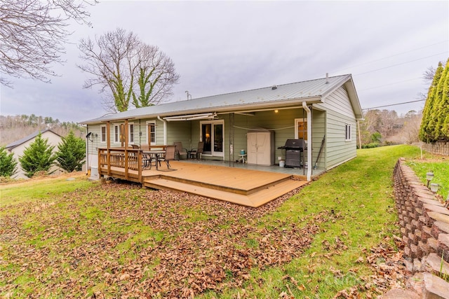 back of house with metal roof, a yard, and a deck