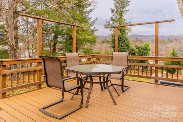 wooden deck featuring a mountain view and outdoor dining area