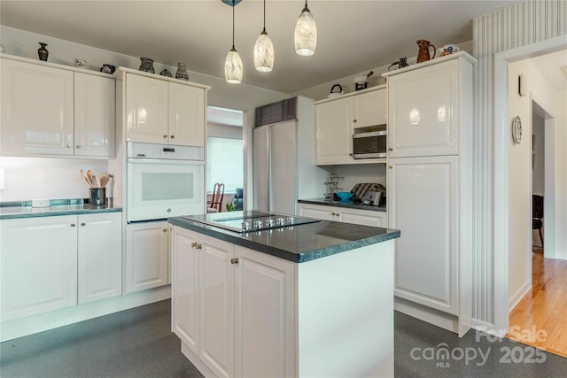 kitchen with stainless steel microwave, white cabinets, dark countertops, and oven