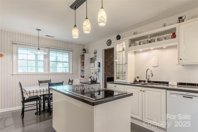 kitchen featuring visible vents, a sink, dark countertops, white dishwasher, and black electric cooktop