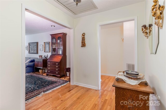 hallway with visible vents, baseboards, and light wood-style flooring