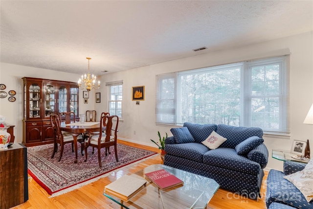 living room with a chandelier, visible vents, a textured ceiling, and wood finished floors