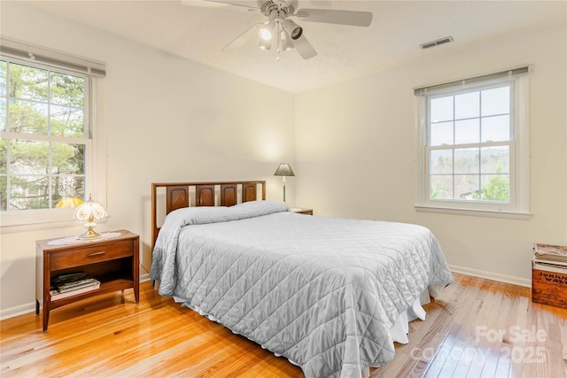 bedroom featuring multiple windows, baseboards, visible vents, and light wood-type flooring