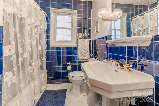 full bathroom with curtained shower, toilet, and tile walls