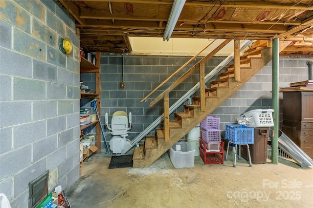 unfinished below grade area featuring concrete block wall and stairs