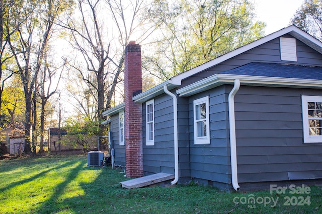 view of side of property featuring cooling unit and a yard