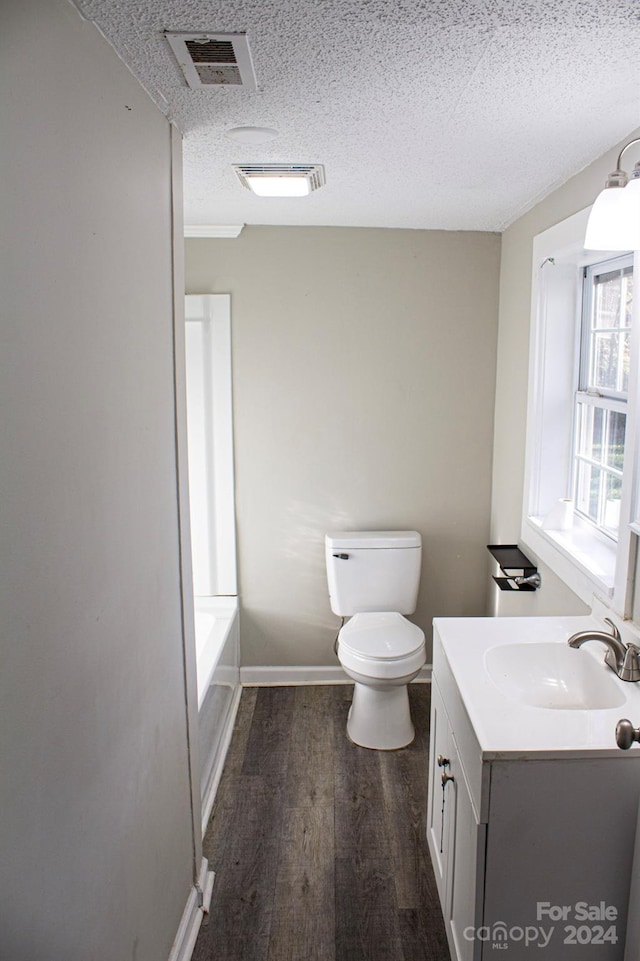 bathroom featuring vanity, a bathtub, hardwood / wood-style flooring, toilet, and a textured ceiling