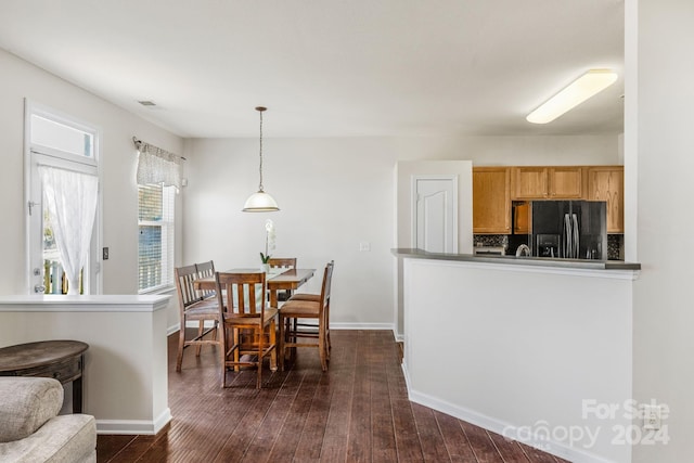 kitchen with decorative light fixtures, dark hardwood / wood-style flooring, black refrigerator with ice dispenser, and tasteful backsplash