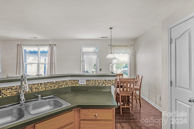 kitchen with decorative backsplash, dark hardwood / wood-style flooring, sink, and hanging light fixtures