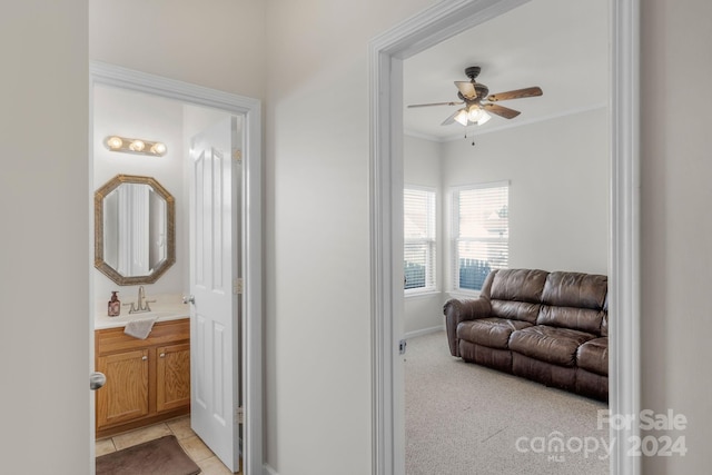 hallway featuring sink, crown molding, and light carpet